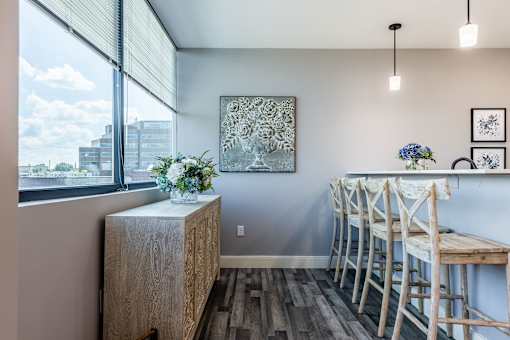 A room with a wooden cabinet, chairs, and a painting on the wall.