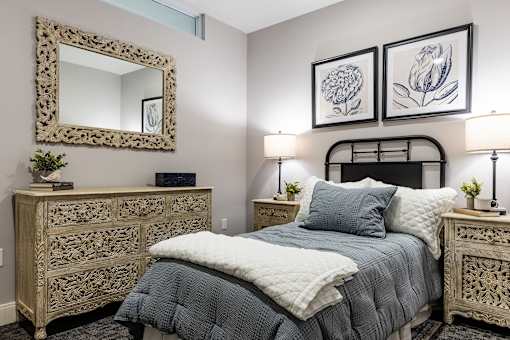 A bedroom with a bed, nightstands, and a mirror.