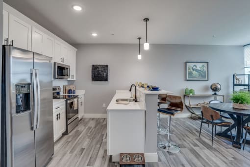 an open kitchen and dining area with stainless steel appliances and a table and chairs