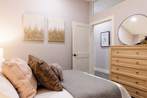 A bedroom with a bed, two pillows, a dresser, and a mirror.