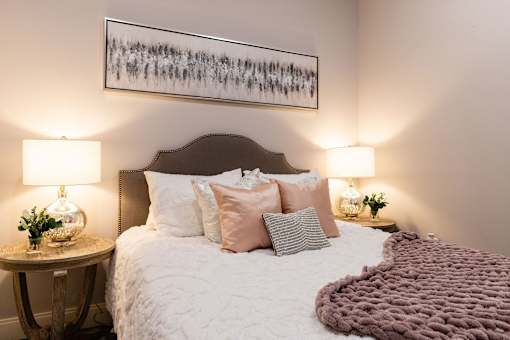 A bedroom with a large bed and a painting above it.