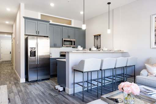 A modern kitchen with a bar stool and a fridge.
