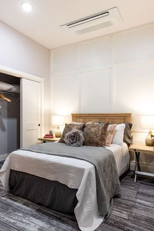 A bedroom with a bed, pillows, and a nightstand.