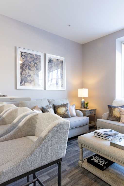 A living room with a grey sofa, a white armchair, a wooden coffee table, and two framed pictures on the wall.