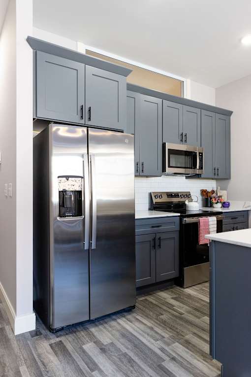 A kitchen with a stainless steel refrigerator and cabinets.