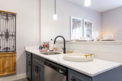 A modern kitchen with a white countertop and a black faucet.