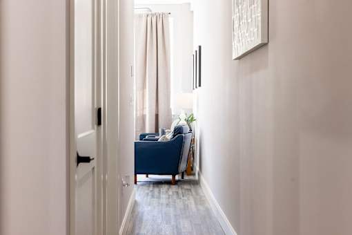 A hallway with a blue couch and a painting on the wall.