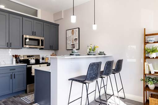 A kitchen with a white island and black barstools.