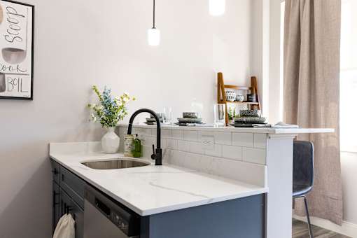 A kitchen with a sink and a framed poster on the wall.