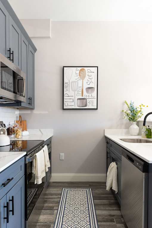 A kitchen with a framed picture on the wall.