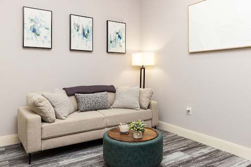 A living room with a couch, a table, and three paintings on the wall.
