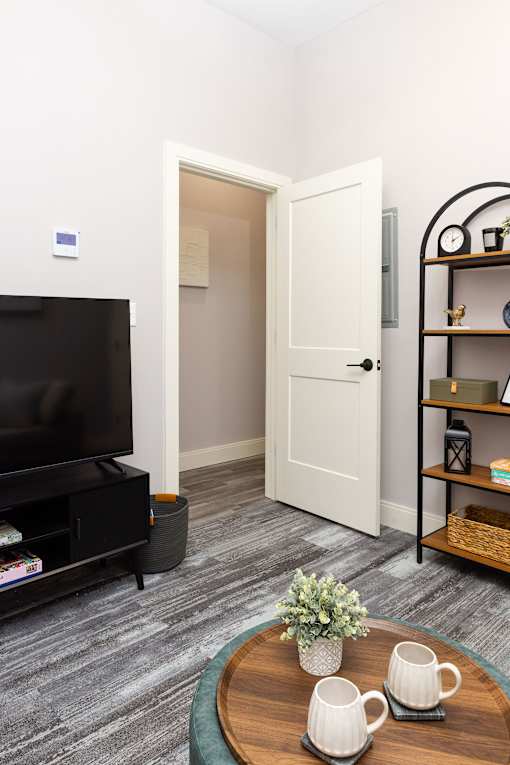 A living room with a grey carpet and a wooden coffee table.