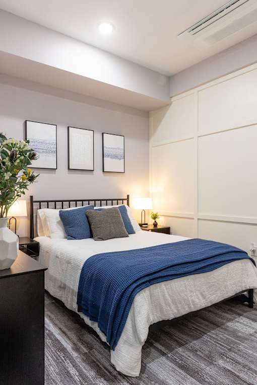 A bedroom with a bed, nightstands, and a plant.