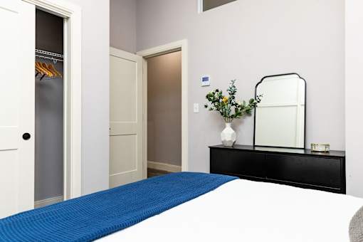 A bedroom with a blue bedspread and a black dresser.