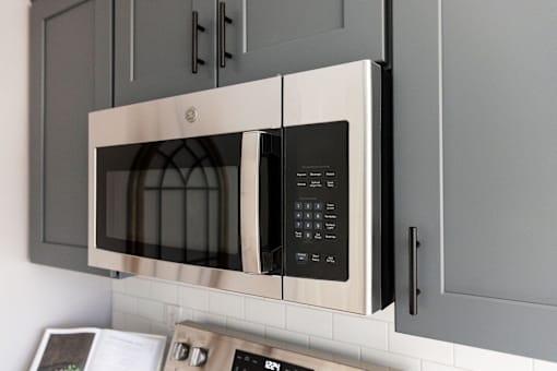A modern stainless steel microwave oven with digital display and control panel.