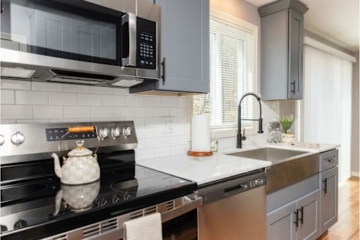 A modern kitchen with a black stove top and a black microwave above it.