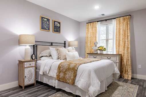 A bedroom with a large bed and a nightstand with a lamp.