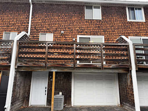 A white garage door is on the ground floor of a house.