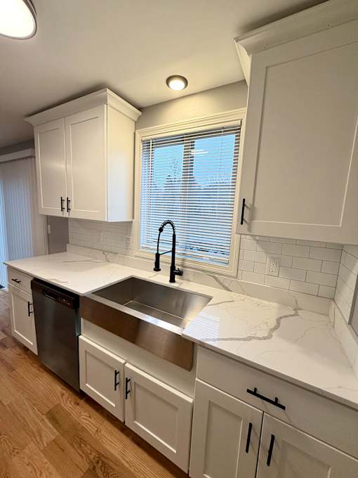 A kitchen with white cabinets and a marble countertop.