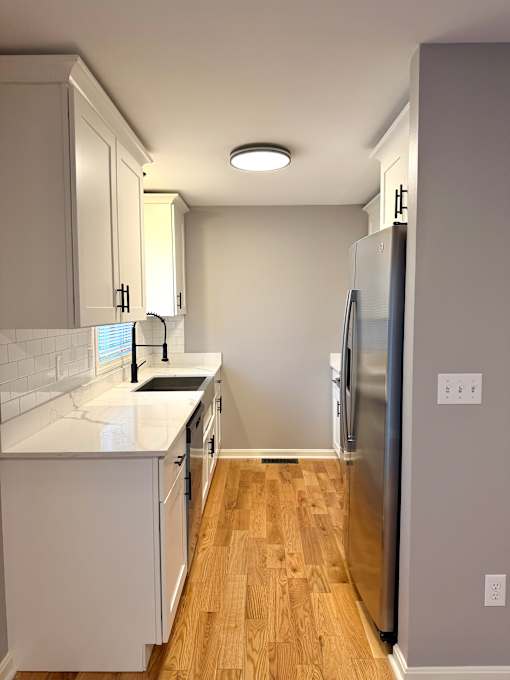 A kitchen with white cabinets and a stainless steel refrigerator.