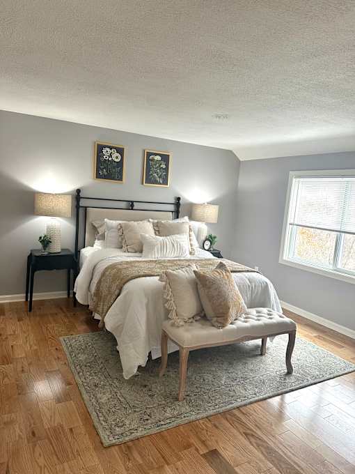 A bedroom with a large bed and a bench.
