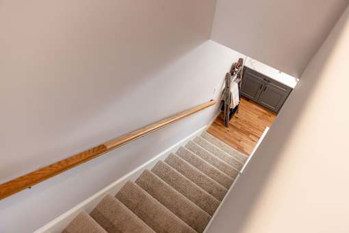 A staircase with a beige carpet and wooden handrail.