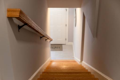 A wooden staircase with a handrail and a door at the end.