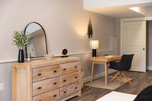 A wooden dresser with a mirror and a lamp on top of it.