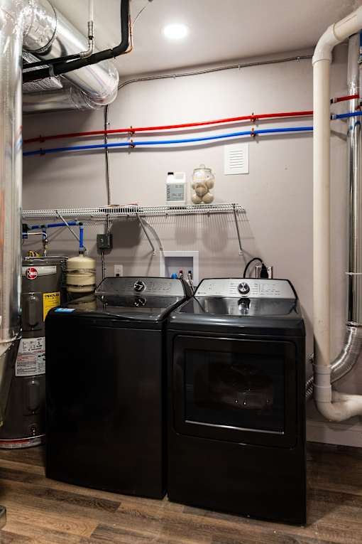 A black oven and sink in a room with pipes.