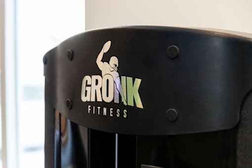 A black cylindrical object with the text "GRONK FITNESS" and a logo of a person doing a squat.
