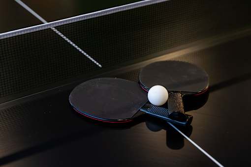 A ping pong ball is in the middle of a table with two paddles.