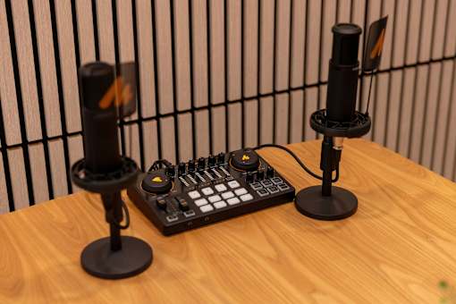 Two microphones stand on either side of a sound mixing board.
