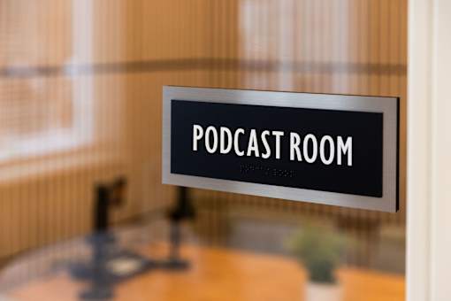 A sign that says Podcast Room is hanging on a wall.