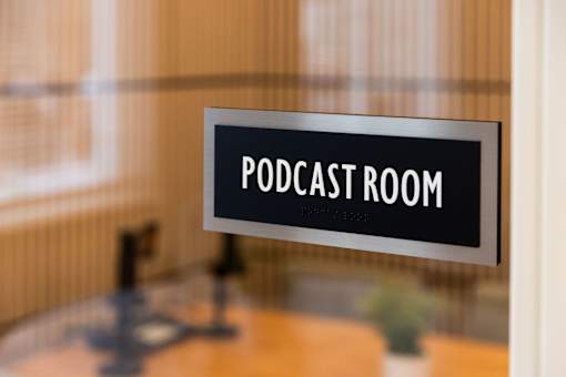 A sign that says Podcast Room is hanging on a wall.