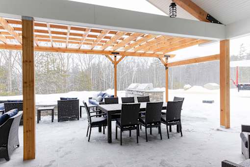 A wooden pergola with a table and chairs underneath it.