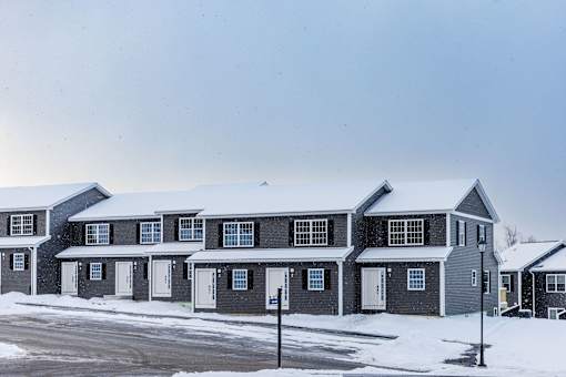 A row of houses with snow on the roofs and driveways.