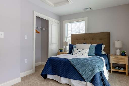 A bedroom with a bed, nightstand, and window.