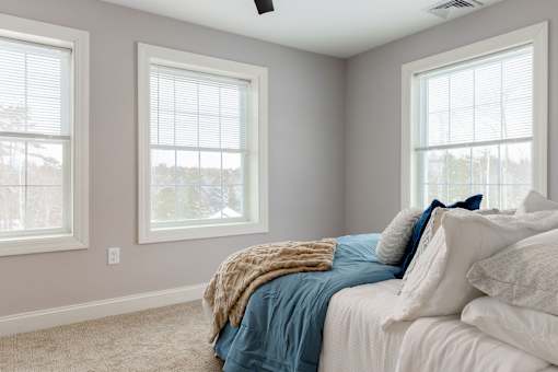 A bedroom with a bed, pillows, and a window.