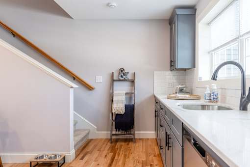 A kitchen with a staircase on the left side.
