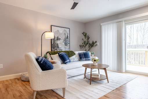 A living room with a white chair, a white couch, and a wooden coffee table.