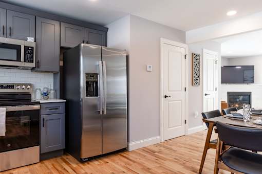 A modern kitchen with a stainless steel refrigerator and wooden flooring.