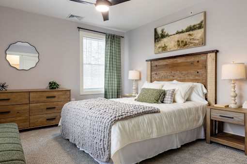 A bedroom with a large bed, a wooden headboard, and a painting on the wall.