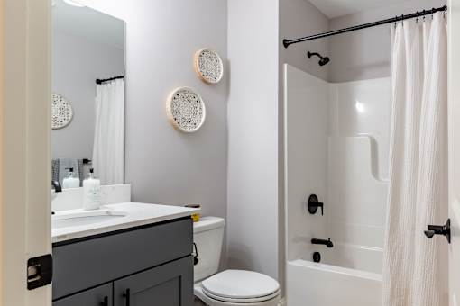 A bathroom with a white toilet, a white sink, and a white shower curtain.
