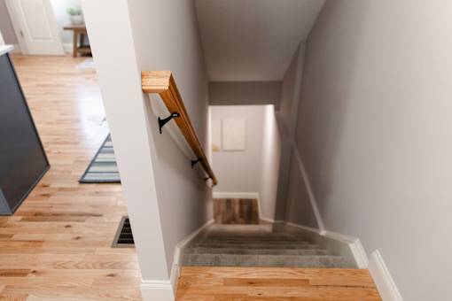 A staircase with a wooden handrail and steps leading down to a landing.