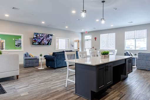 A reception area with a white counter and blue chairs.