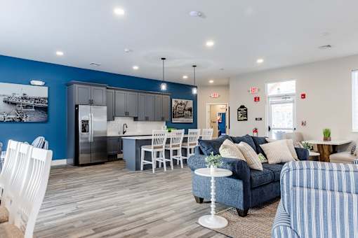 A blue kitchen with white chairs and a blue couch.