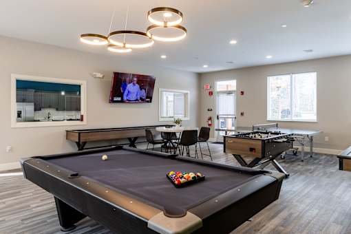 A pool table in a room with a television mounted on the wall.