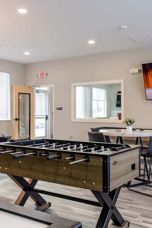 A foosball table is in the middle of a room with a dining table and chairs.