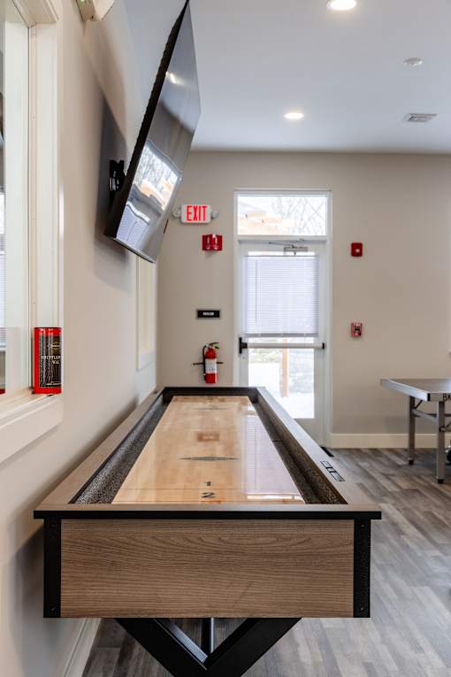 A pool table in a room with a tv mounted on the wall.