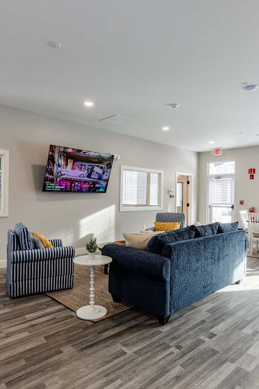 A living room with a blue couch and a television mounted on the wall.